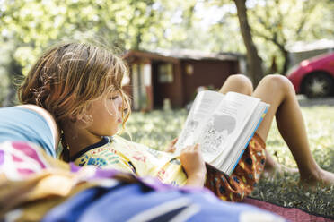 Blonder Junge, der neben seiner Mutter im Wald liegt und ein Buch liest - PCLF00771