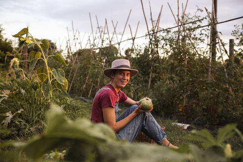 Happy woman holding round zucchini in orchard - PCLF00794