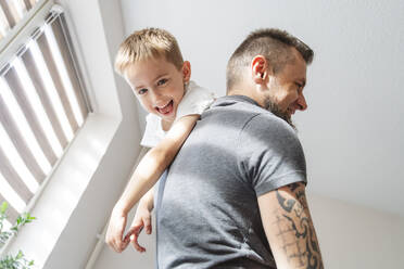 Verspielter Vater trägt seinen Sohn zu Hause auf der Schulter - IHF01760