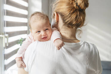 Smiling newborn baby resting on mother's shoulder at home - IHF01761