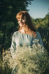 Smiling redhead young woman with flowers on a sunny day - ADF00184