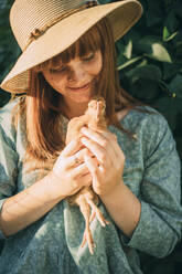 Young woman with freckles holding chicken - ADF00191