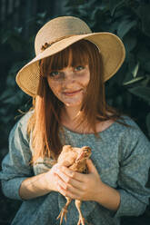 Young redhead woman with freckles holding chicken - ADF00192