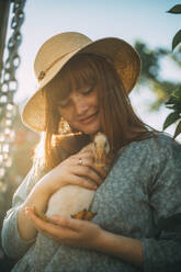 Young woman wearing hat holding duckling - ADF00193