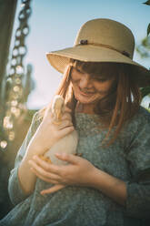 Smiling young woman with freckles holding duckling - ADF00194