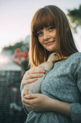 Young woman with freckles holding duckling - ADF00196