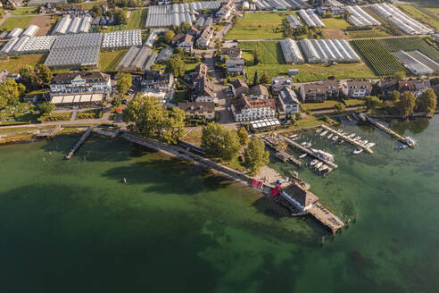 Deutschland, Baden-Württemberg, Luftaufnahme von Stegen am Ufer der Insel Reichenau mit Gewächshäusern im Hintergrund - WDF07405