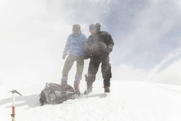 Männer mit Rucksack wandern auf einem Berg im Schnee - PCLF00852