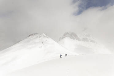 Männer wandern auf schneebedecktem Berg unter Himmel - PCLF00853