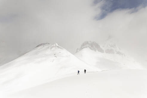 Männer wandern auf schneebedecktem Berg unter Himmel - PCLF00853