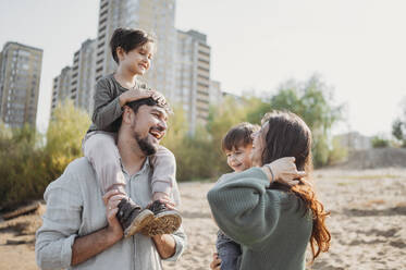 Happy mother and father enjoying with children at beach - ANAF02249