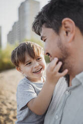 Glücklicher Sohn genießt mit Vater am Strand - ANAF02251