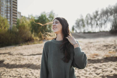 Happy woman standing at beach on sunny day - ANAF02253