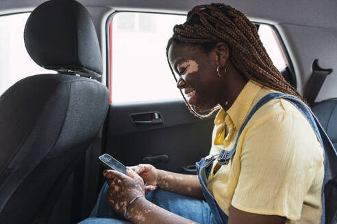 Lächelnde Frau benutzt Smartphone im Auto - PNAF06036