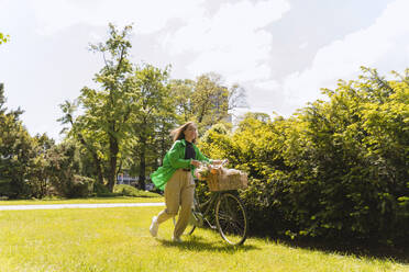 Woman with bicycle in park on weekend - NDEF01223