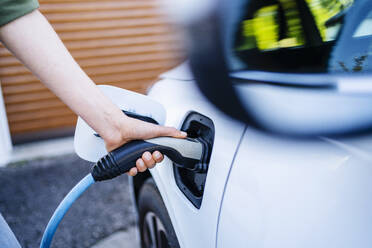 Hand of woman charging electric car - DIGF20874