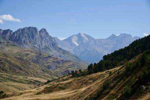 Rough rocky Anayet peak mountain range covered with grass located against cloudless blue sky in nature of Aragon Pyrenees in Spain - ADSF48182