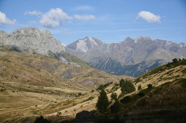 From above rough rocky of Garmo Negro mountain range covered with grass located against blue sky in nature of Aragon Pyrenees in Spain - ADSF48188