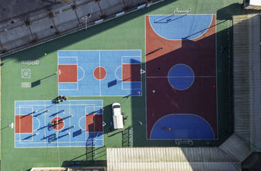 Drone view of track parked near colorful football pitches of different sizes with lines in daylight - ADSF48215