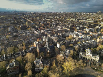 Scenic aerial view of Amsterdam city with residential buildings and green trees under cloudy sky - ADSF48227