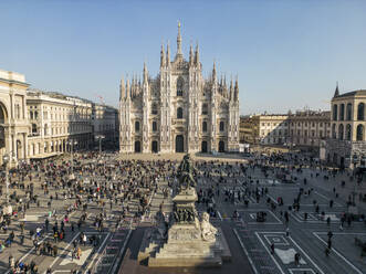 Aerial view of Milan with crowd near old buildings and Metropolitan Cathedral-Basilica of Nativity of Saint Mary in Italy in daylight - ADSF48235