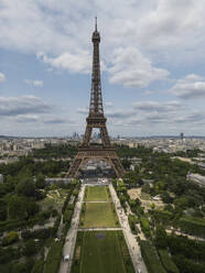 Picturesque view of famous Eiffel Tower located on green hill against cloudy sky in Paris - ADSF48240