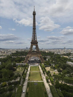 Picturesque view of famous Eiffel Tower located on green hill against cloudy sky in Paris - ADSF48240