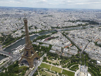 Picturesque view of famous Eiffel Tower located on green hill against cloudy sky in Paris - ADSF48242