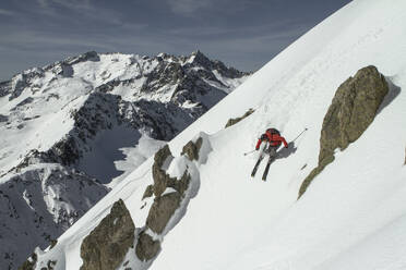 High angle of anonymous man riding skis on snowy mountain on winter day - ADSF48255