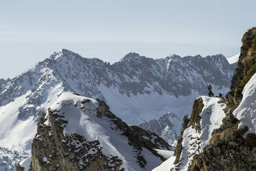 Side view of unrecognizable person with snowboard standing on snowy mountain while looking away admiring landscape - ADSF48257