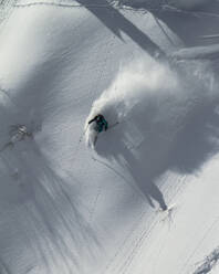 Top view of anonymous man riding skis on snowy mountain on winter day - ADSF48261