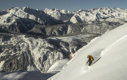 Side view of unrecognizable sportsman riding snowboard on snowy mountain in winter - ADSF48263