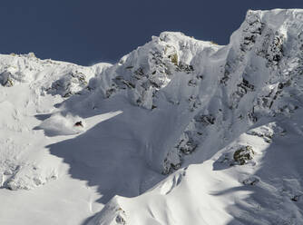 Full body of anonymous man riding skis on snowy mountain on winter day - ADSF48265