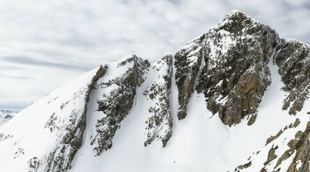 Picturesque landscape of rocky rough mountains covered with snow against cloudy sky during winter day - ADSF48269