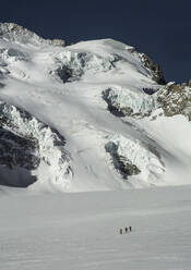 Back view of anonymous people riding skis on snowy mountain on winter day - ADSF48270