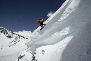 From below of anonymous snowboarder in warm ski suit and with snowboards doing sport in the on snowy mountains in Ushuaia Argentina - ADSF48283