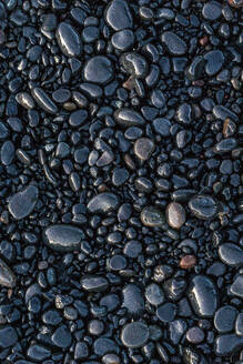 Top view of wet stones located near smooth sedimentary rock on coast in Reynisfjara Beach - ADSF48352