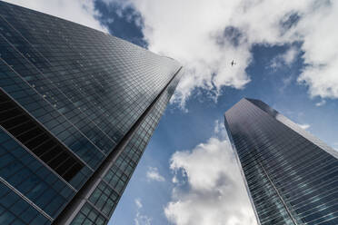 From below contemporary high rise structures with glass mirrored walls against cloudy blue sky - ADSF48368