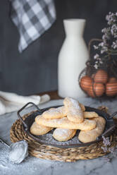 Tray with crunchy ladyfingers finger sponge cake placed on table near eggs and jar on gray background in kitchen at home - ADSF48385