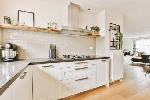 Interior of modern kitchen with stove and kitchenware on counter with white cabinets in contemporary apartment - ADSF48396