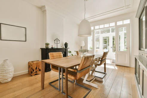 Interior of modern dining room with wooden table and chairs arranged while pendant light hanging from ceiling at apartment - ADSF48407