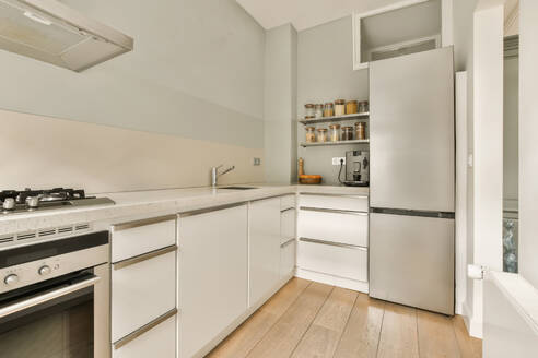 Interior of light kitchen with white cabinets and stainless steel refrigerator at contemporary apartment - ADSF48416
