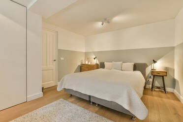 Interior of illuminated bedroom with white bed surrounded with white walls in modern spacious apartment - ADSF48418