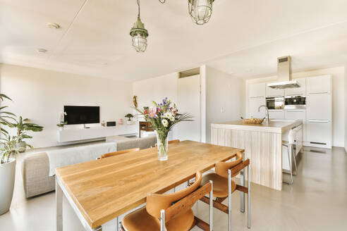 Flower vase on wooden table in dining room in front of living room at contemporary home - ADSF48439