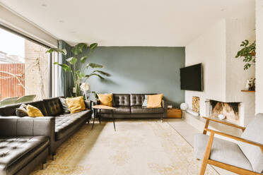 Interior of spacious living room with leather couches and fireplace with television in contemporary apartment - ADSF48445