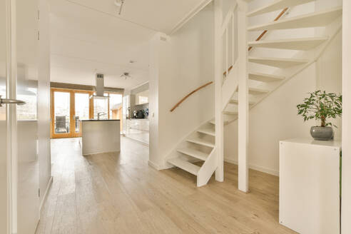 Interior of modern house with white staircase by kitchen seen through passageway - ADSF48454