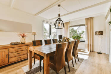 Interior of dining room with pendant light hanging over wooden table at contemporary home - ADSF48476