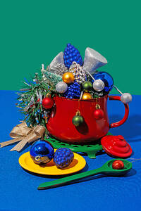Christmas table setting with different colorful ornaments placed in red pot against blue and green background - ADSF48486
