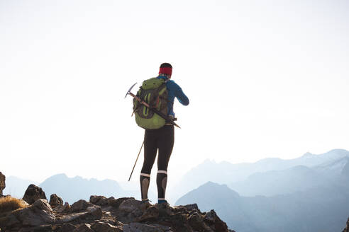 Mature man standing with backpack on mountain - PCLF00864