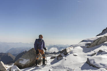 Mature man standing with hiking pole on mountain - PCLF00868